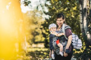Mama en baby in draagzak in het bos
